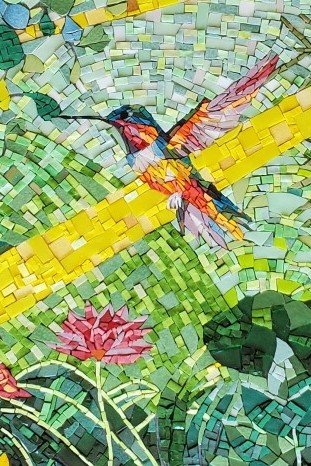 Détail d'une fresque en mosaïque représentant un colibri coloré traversé par un rayon de soleil jaune.