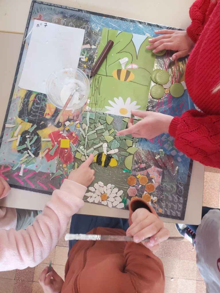 quatre mains d'enfants réalisent une oeuvre en mosaïque lors d'un atelier avec la mosaïste Céline Loury