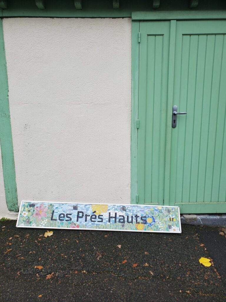 fresque en mosaïque où c'est écrit le nom de l'école les prés hauts, cette mosaïque est par terre avant de la poser sur le mur de l'école de Juigné sur Sarthe