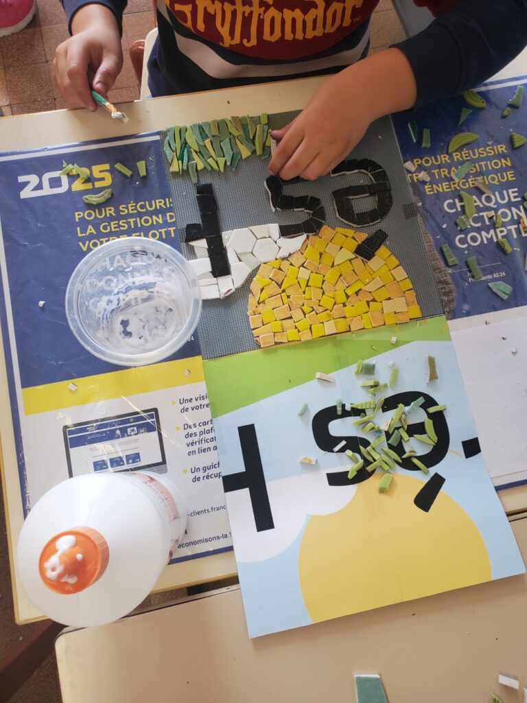 deux mains d'enfants qui collent de la mosaïque sur un modèle