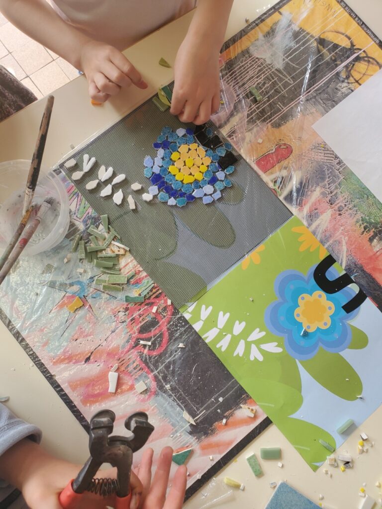 deux mains d'enfants qui réalisent une fresque en mosaïque