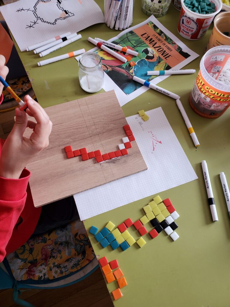 début d'un perroquet en pixel art en cours de réalisation, l'enfant est en train de poser des morceaux