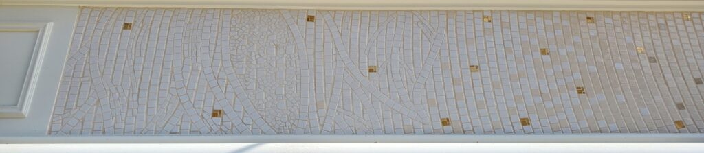 détail d'une enseigne en mosaïque en émaux blancs avec une feve de cacao, en blanc sur joint ton pierre. Enseigne réalisée par Céline Loury
