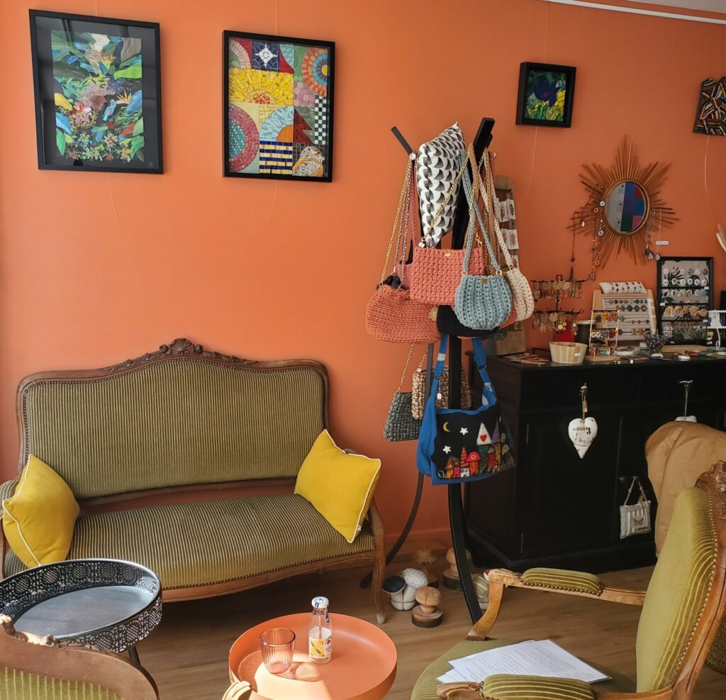 salon de thé le bazar où l'on papote à Précigné en Sarthe, photo d'une table avec fauteuils, et deux tableaux de l'artiste Céline Loury en mosaïque