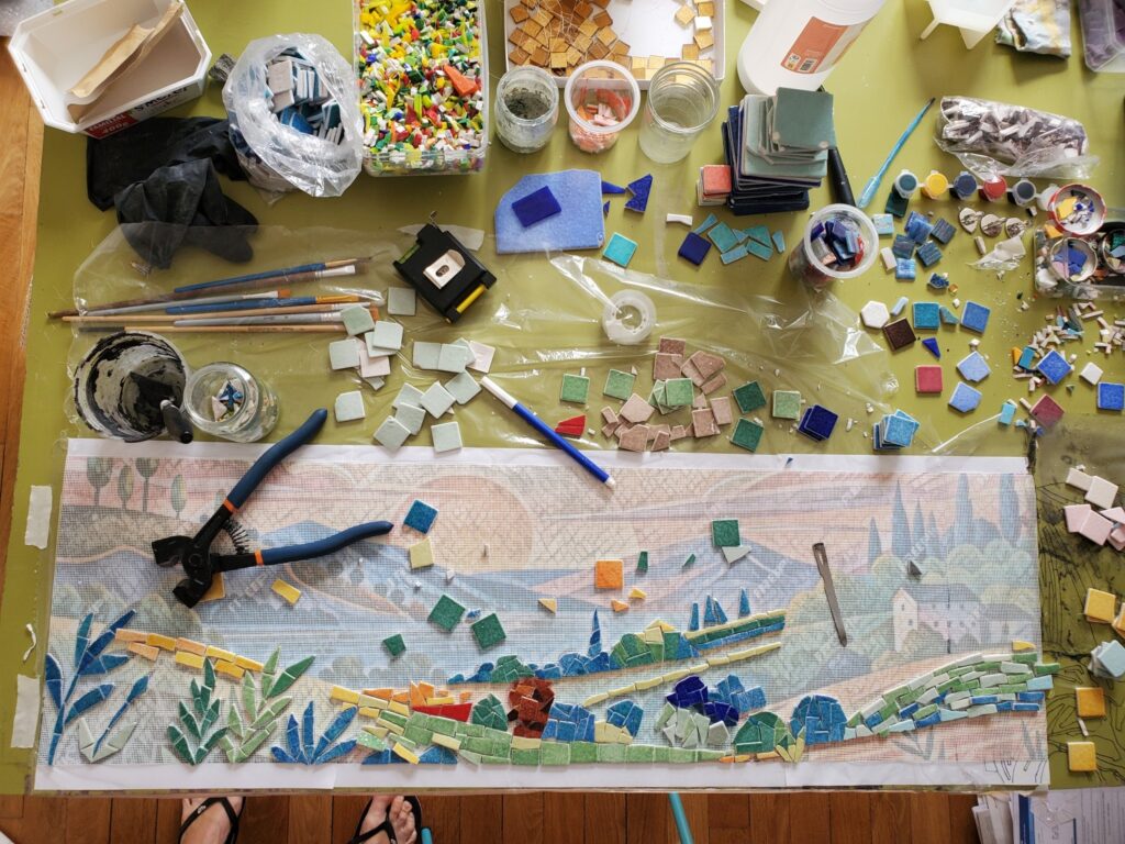 plan de travail vue du dessus avec une pince à mosaïque et le gabarit avec le filet pour coller la mosaïque. Atelier de Céline Loury, mosaïste